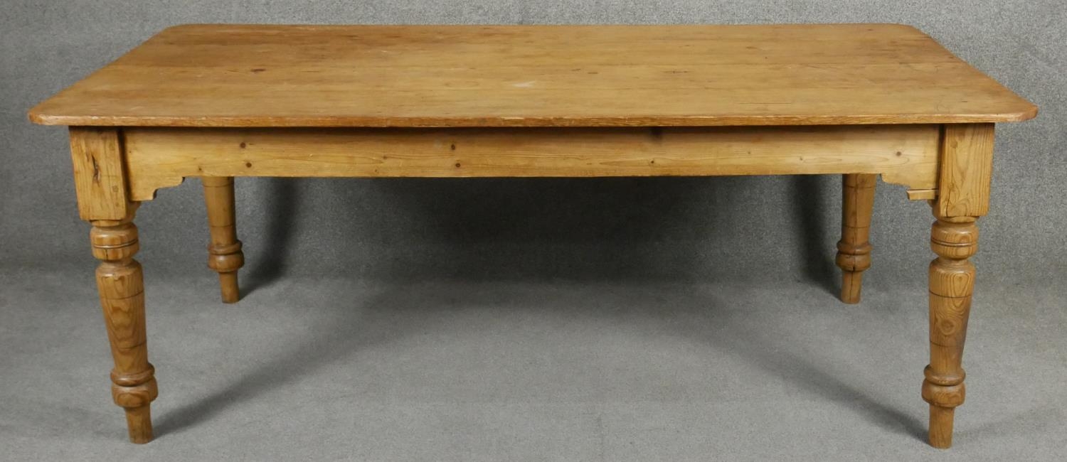 A 19th century pitch pine planked top farmhouse refectory style dining table on turned tapering