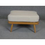 A vintage light beech Ercol style footstool with fitted cushion. L72 W52 H38cm (Damage to webbing as