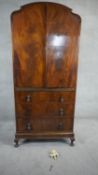 A mid century burr walnut Queen Anne style linen cabinet with panel doors enclosing shelves above