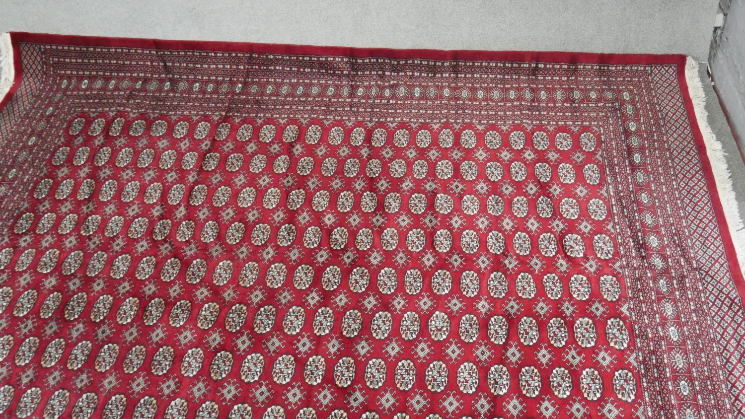 A Bokhara carpet with repeating gul motifs on a burgundy ground within multiple borders. L.358 W. - Image 3 of 5