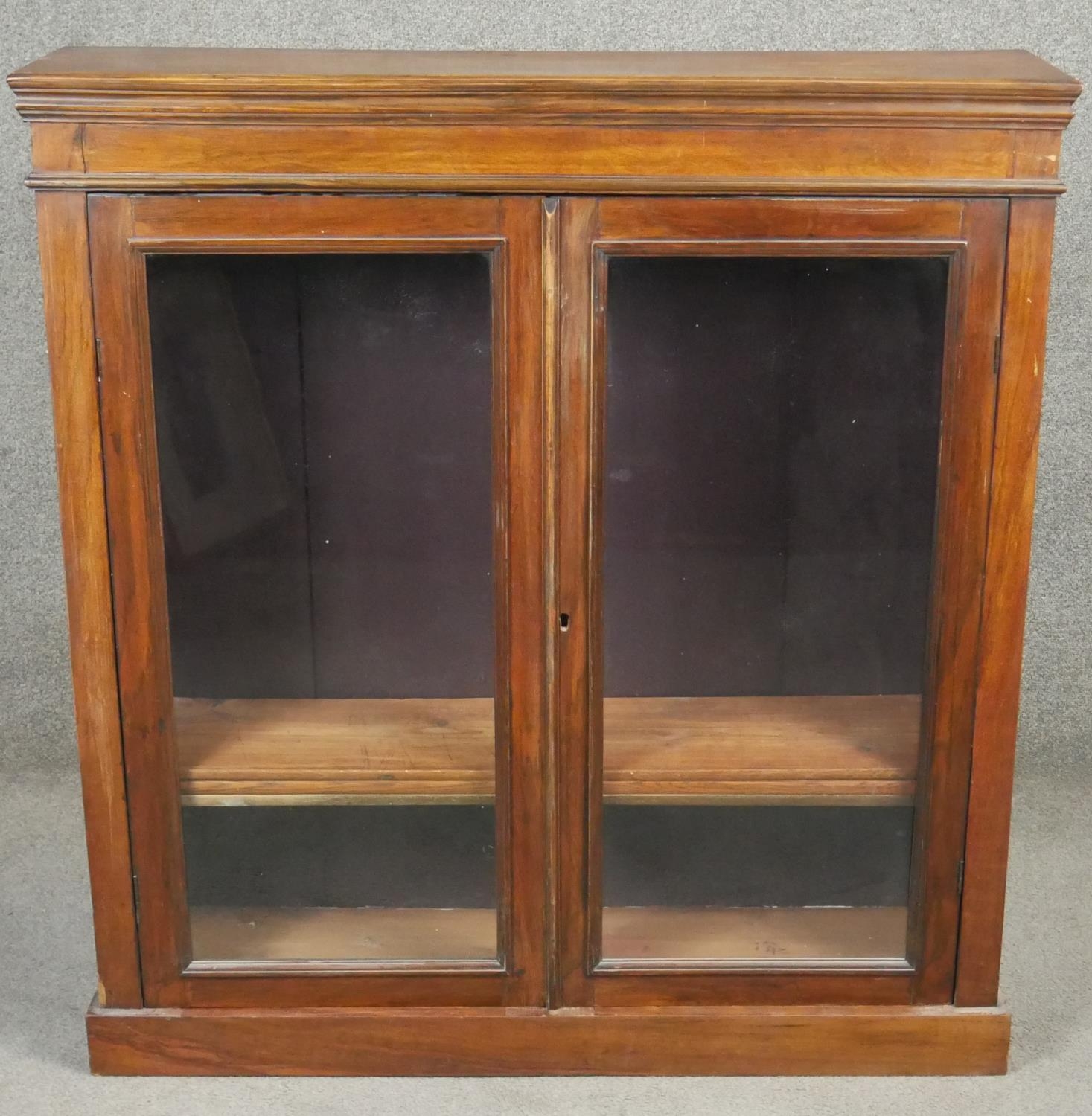 A late 19th century walnut glazed bookcase on plinth base. H.110 W.103 D.24cm