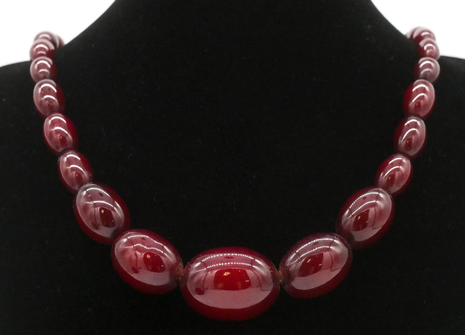 A vintage 30 inch cherry amber bakelite graduated necklace with silver lobster clasp, stamped 925.