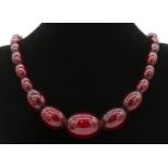 A vintage 30 inch cherry amber bakelite graduated necklace with silver lobster clasp, stamped 925.
