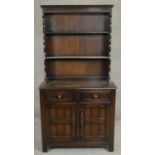 A mid century Jacobean style oak dresser with upper open plate rack above base fitted with drawers
