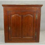 A Georgian oak hanging corner cabinet with twin arched fielded panel doors enclosing shelves. H.