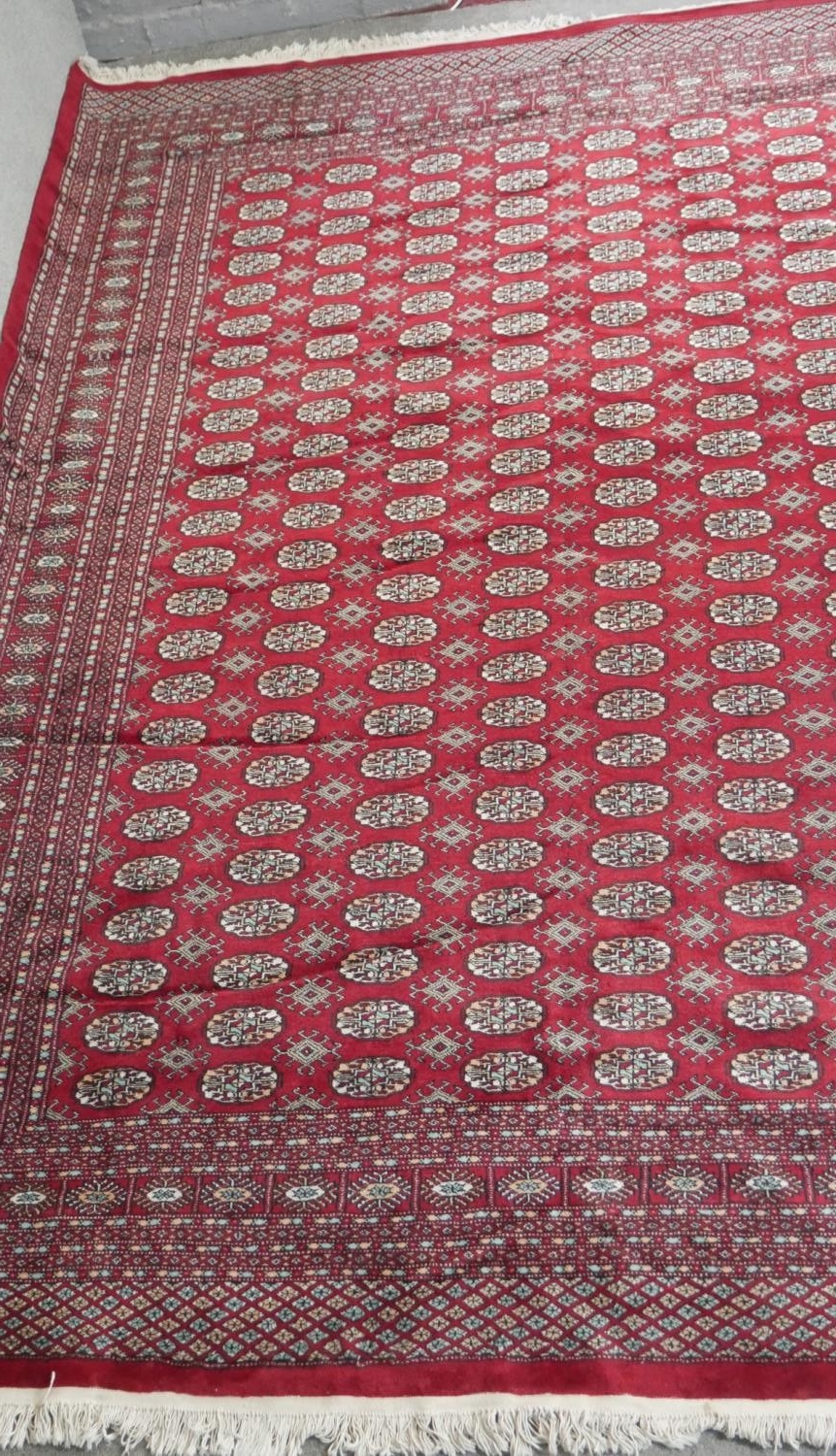 A Bokhara carpet with repeating gul motifs on a burgundy ground within multiple borders. L.358 W.