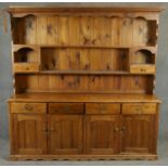A 19th century style pine dresser with open plate rack above base fitted with drawers and cupboards.