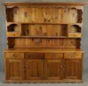 A 19th century style pine dresser with open plate rack above base fitted with drawers and cupboards.