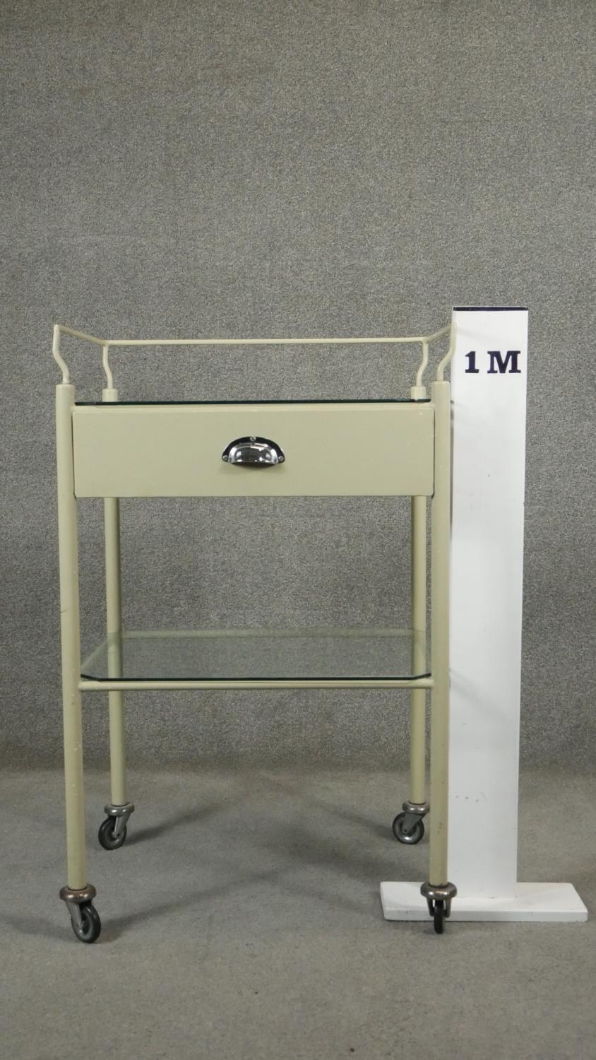 A vintage medical style trolley with back rail and glass top and undertier on casters. H.98 W.62 D. - Image 4 of 4