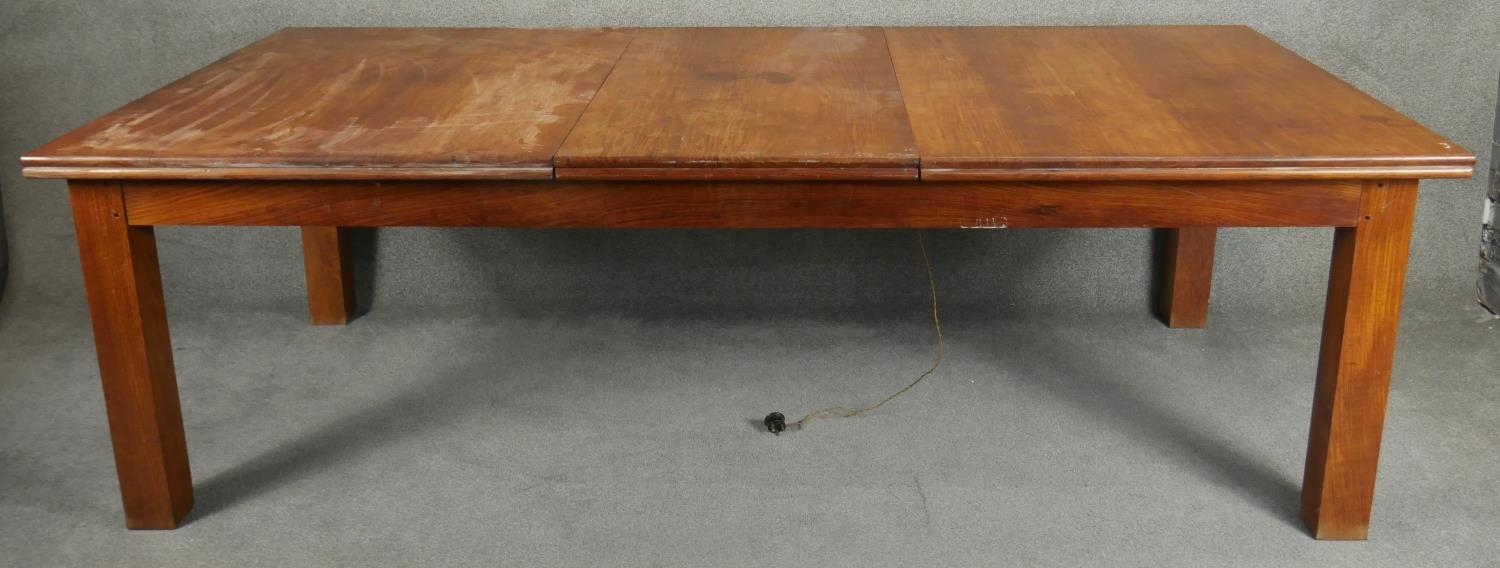 A large hardwood dining table on square supports with fixed central leaf. H.76 L.245 D.122cm