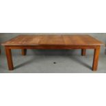 A large hardwood dining table on square supports with fixed central leaf. H.76 L.245 D.122cm