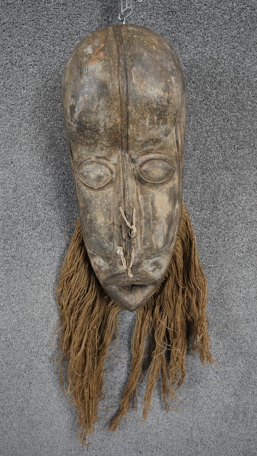A vintage Republic of Congo carved wooden tribal mask with straw fibre beard and cowrie shell