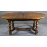 An antique style Ipswich oak extending dining table with two extra leaves on baluster turned