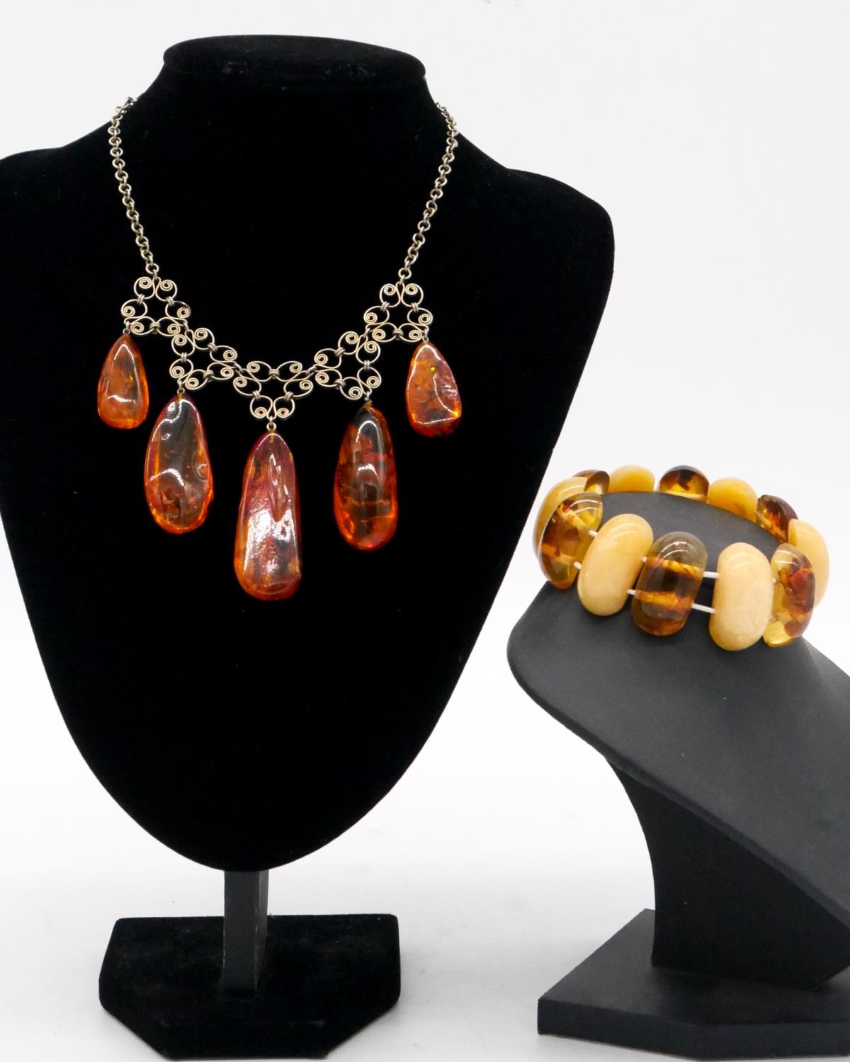 An amber bead elasticated bracelet along with a graduated amber drop necklace with scrolling