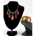 An amber bead elasticated bracelet along with a graduated amber drop necklace with scrolling
