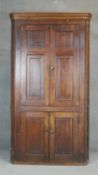 A Georgian country oak full height floor standing corner cupboard with panel doors enclosing