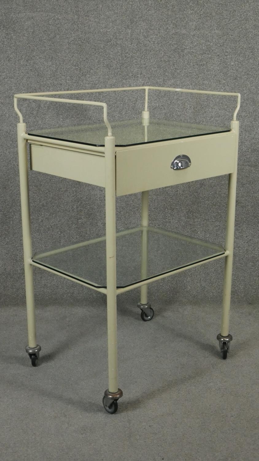 A vintage medical style trolley with back rail and glass top and undertier on casters. H.98 W.62 D. - Image 2 of 4