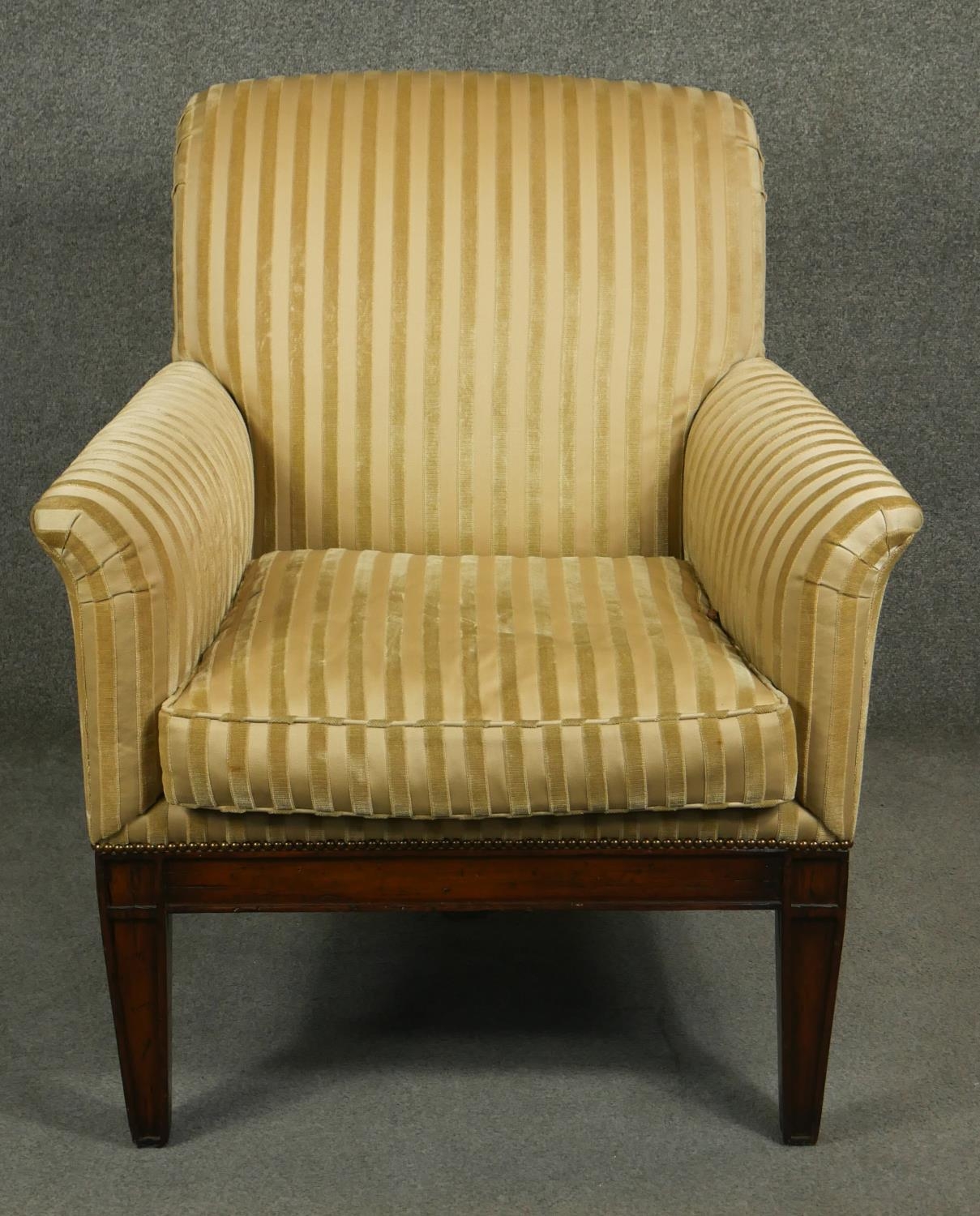 A Regency style mahogany upholstered library armchair on square tapering supports and sabre supports