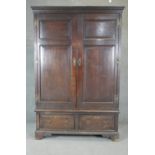 A Georgian country oak press cupboard with fielded panel doors above base doors on bracket feet.