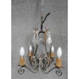 A cast iron scrolling design four branch chandelier with gilded foliate motifs and cut glass