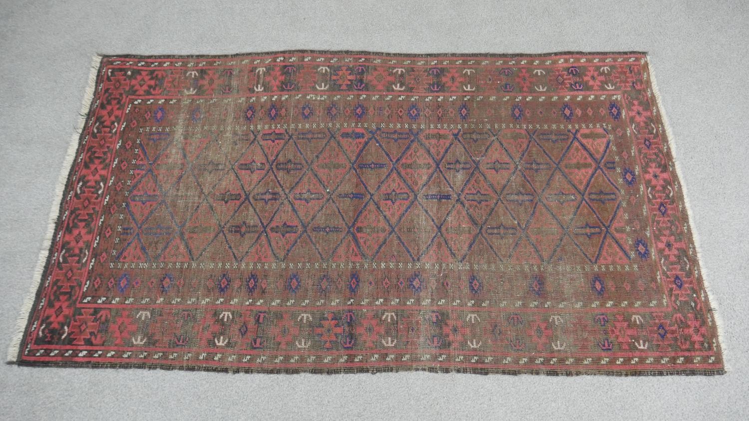 A Persian Belouch rug with repeating diamond design on a madder field within multiple borders. L.157 - Image 2 of 4