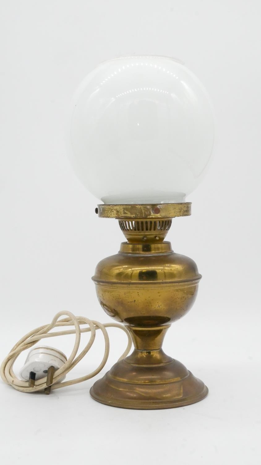 A vintage brass oil lamp with milk glass globe shade converted to electricity. H.38cm