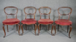 A set of four mahogany balloon back dining chairs on carved cabriole supports.