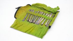 A lime green lined roll containing twelve Edwardian silver handled butter knives, silver plated