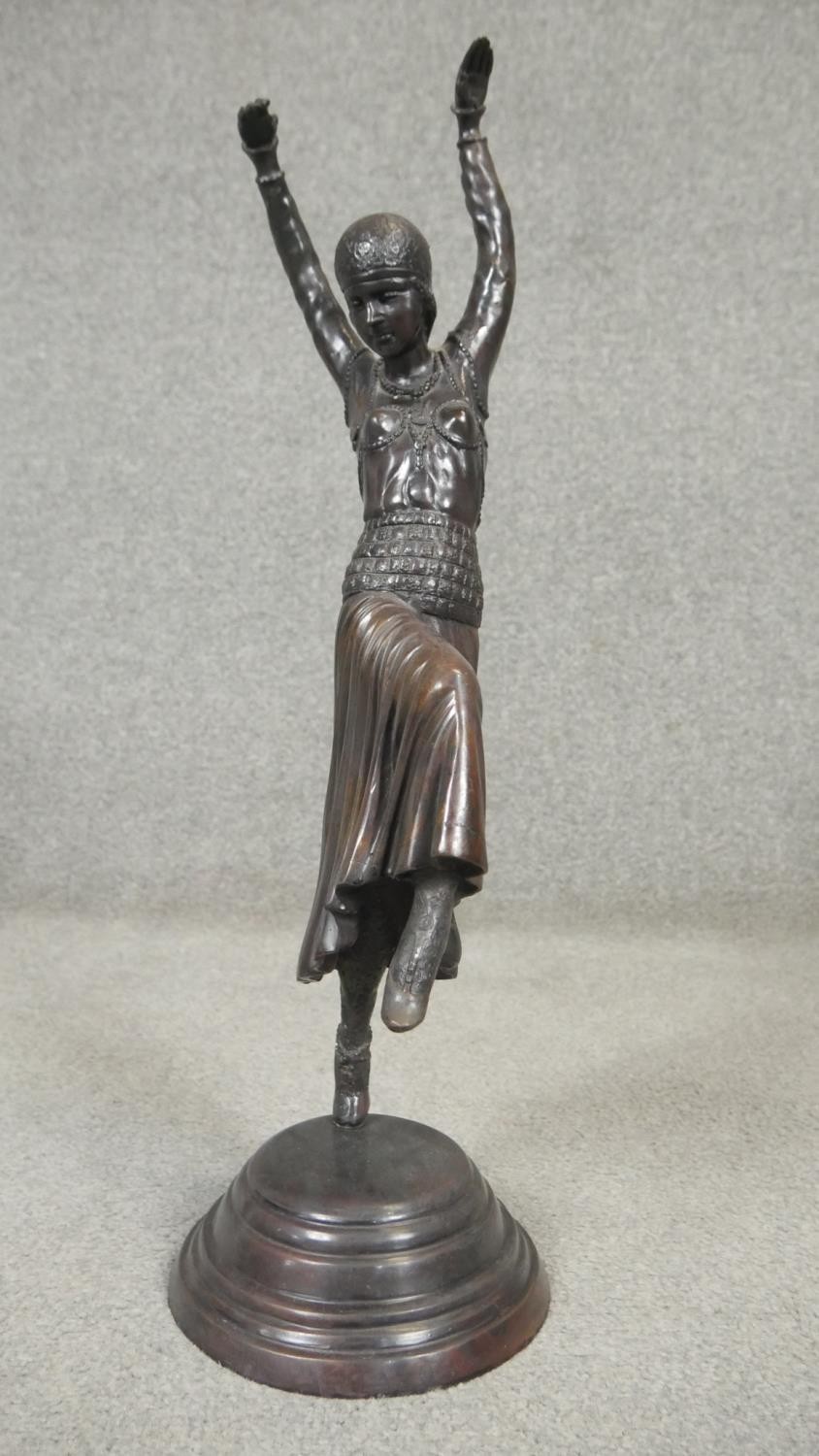 An Art Deco style spelter sculpture of a female dancer in period clothing with headdress, on a