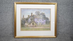 A framed and glazed watercolour on paper of a country cottage covered in Wisteria. Signed E.J.