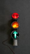 A set of vintage metal framed light up traffic lights with coloured glass fronts. Collar reads