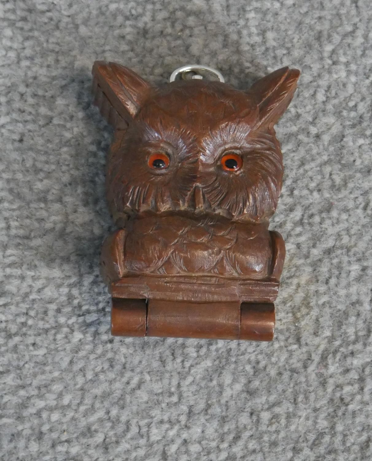 A carved oak Black Forest pocket watch holder in the form of an owls head, with orange glass eyes
