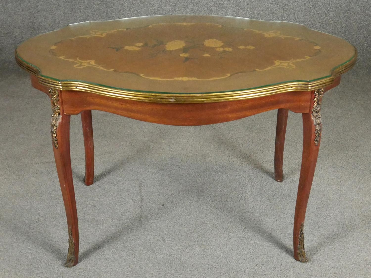 An Italian walnut and floral inlaid occasional table with shaped glass top on ormolu mounted