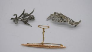 An engraved hollow marked 9ct gold bar brooch and two marcasite flower brooches.