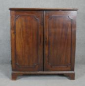 A Georgian mahogany side cabinet with panel doors enclosing open space on bracket feet. H.107 W.96