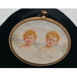 A gilt metal oval framed and glazed miniature pendant of two auburn boys with blue eyes on a