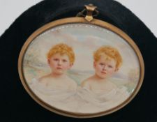 A gilt metal oval framed and glazed miniature pendant of two auburn boys with blue eyes on a