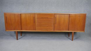 A 1970's vintage teak sideboard with a bank of central drawers flanked by sliding cupboard doors