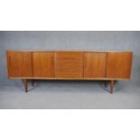 A 1970's vintage teak sideboard with a bank of central drawers flanked by sliding cupboard doors