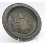 An antique repousse pewter plate with coat of arms and knights armour decoration. D.23cm
