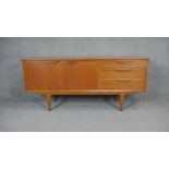 A 1970's vintage teak sideboard with cupboards and drawers on shaped tapering supports. H.74 W.168