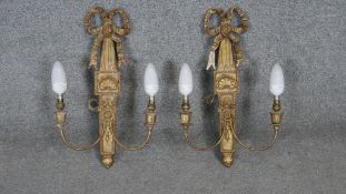 A pair of carved gilt wood twin branch wall sconces with scrolling ribbon and shell decoration.