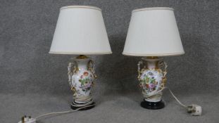 Two hand painted porcelain table lamps with floral bouquet design mounted on a black base. Each with
