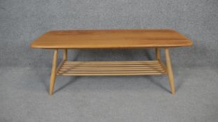 A vintage Ercol coffee table with blonde elm top on beech turned base and magazine rack undertier.
