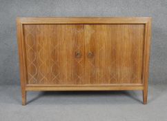 A mid century vintage teak Gordon Russell sideboard with incised decoration to doors enclosing