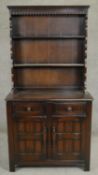 A mid century Jacobean style oak dresser with upper open plate rack above base fitted with drawers