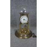 A vintage German anniversary clock under brass dome, with key.