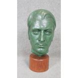 A mid century patinated bronze sculpture of a male head mounted on a polished teak base.
