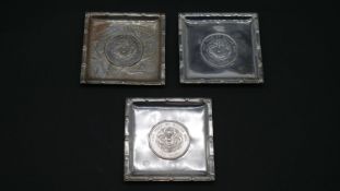 Three Chinese silver square pin trays, each with a Chinese dragon coin to the centre, one with an