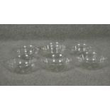 Six cut glass bowls with star cut bases and flared rims.